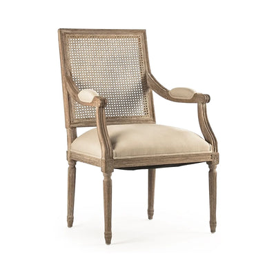 A classic French-style dining armchair with a weathered gray-brown wooden frame, woven cane backrest, and light beige upholstered seat and armrest cushions, shown on a white background.